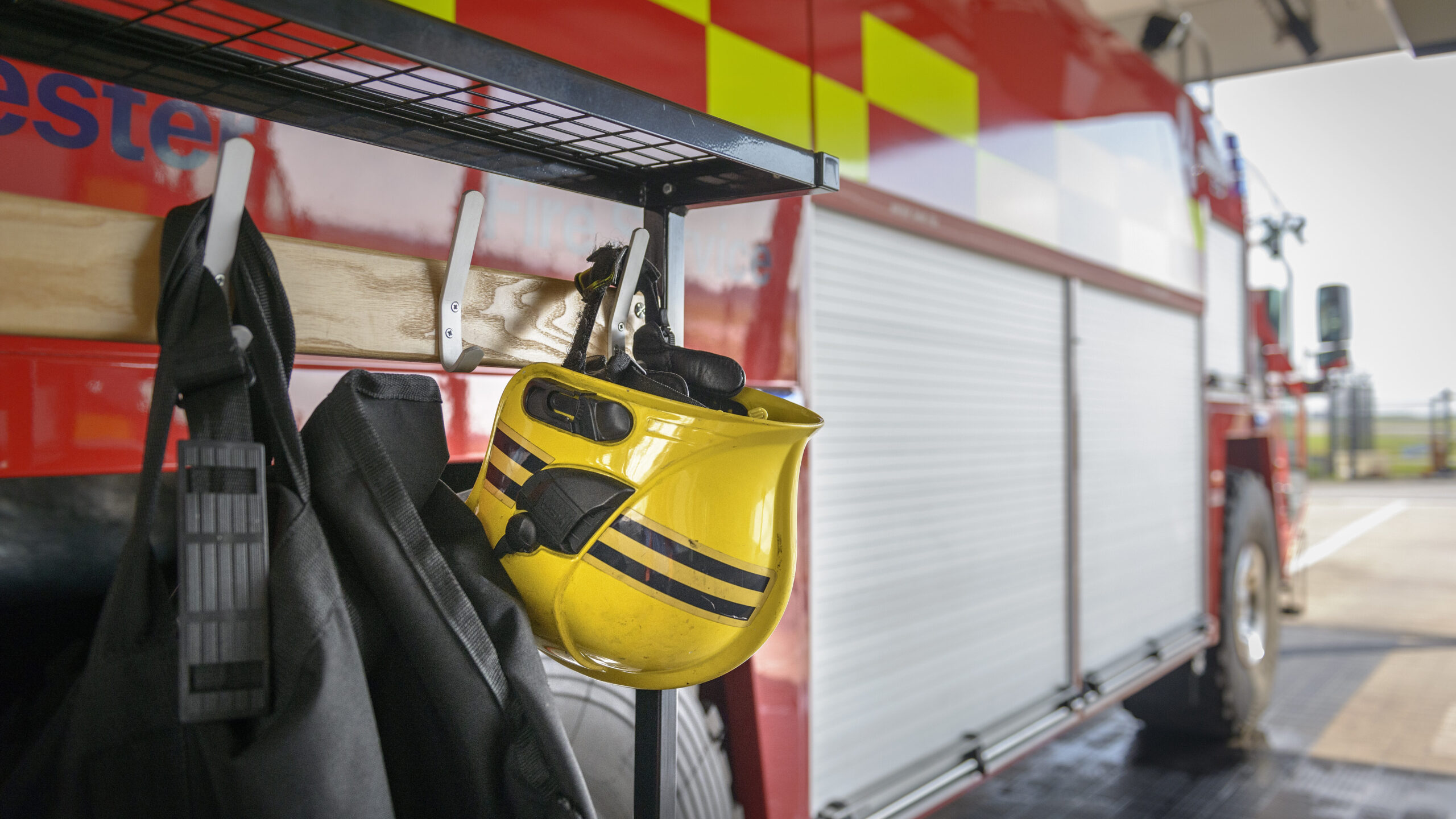 Stationary fire engine with a fireman's helmet hung up in the foreground.