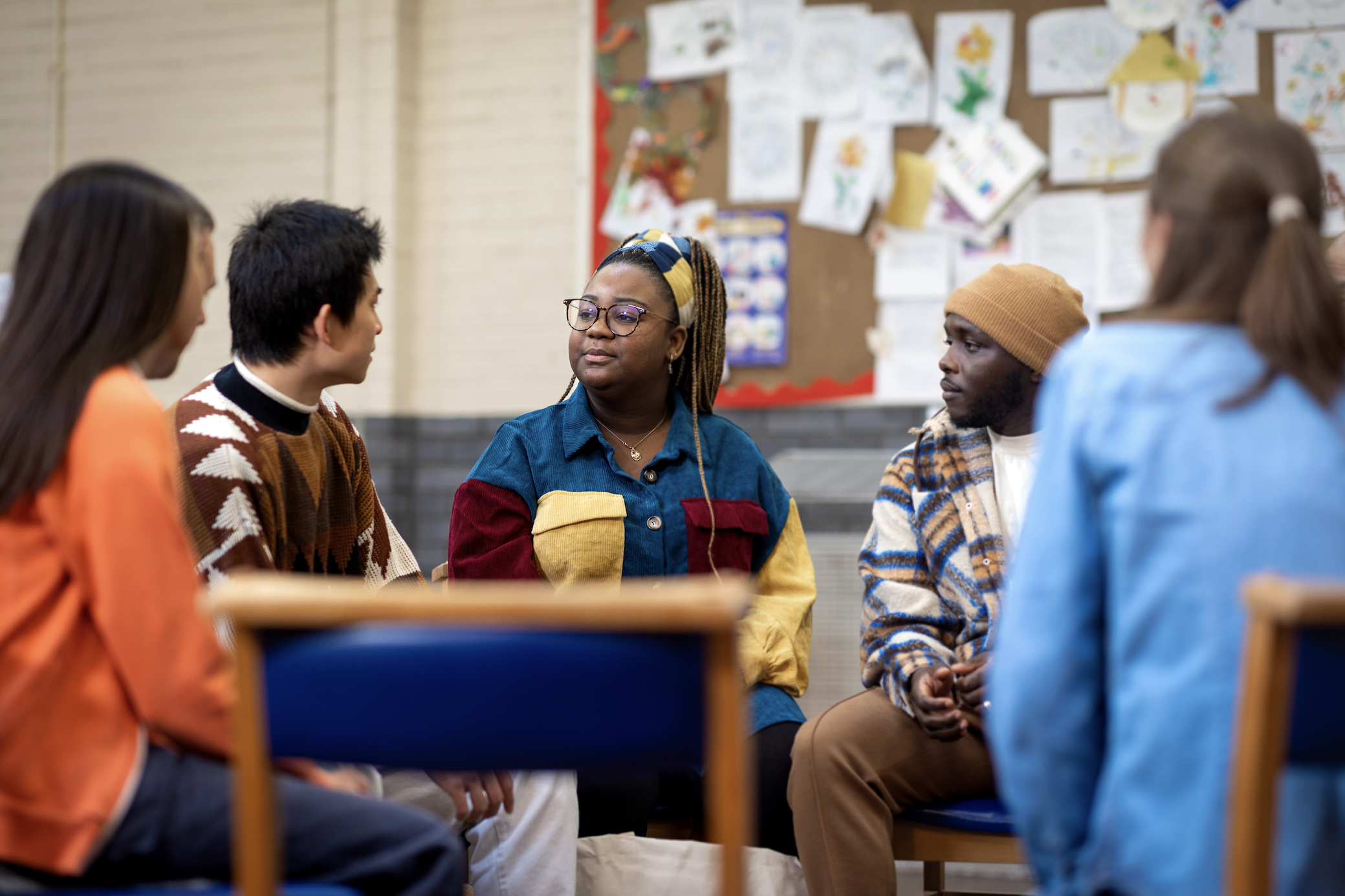 Group of five men and women of various ages in discussion in a community centre.